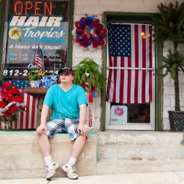 A boy sits on the stoop of the Shoals flower shop during the Catfish festival.
